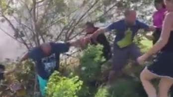 Bystanders form human chain to help driver out of overturned car on Florida highway