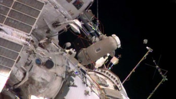Spacewalking astronauts release baby satellite