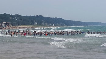 Michigan beachgoers form human chains to rescue swimmers, as 2 drown in rough waves