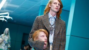 Models carry their own severed heads down the runway