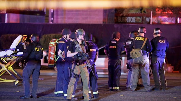 Police officers and medical personnel stand at the scene of a shooting near the Mandalay Bay resort and casino on the Las Vegas Strip, Monday, Oct. 2, 2017, in Las Vegas. Multiple victims were being transported to hospitals after a shooting late Sunday at a music festival on the Las Vegas Strip. (AP Photo/John Locher)