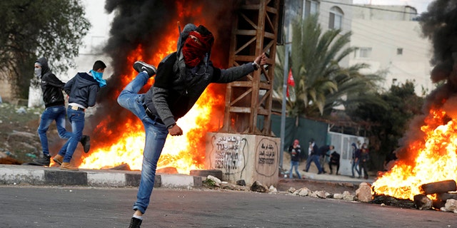 A Palestinian demonstrator hurls stones toward Israeli troops during clashes at a protest against U.S. President Donald Trump's decision to recognize Jerusalem as the capital of Israel, near the West Bank city of Nablus, December 29, 2017