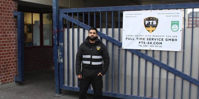 In this Oct. 19, 2016 photo Naji Negmah, a 24-year old asylum seeker from Damascus, stands in front of an asylum seeker home in Berlin where he works as a guard. A start-up company in Berlin is trying to play a role in helping integrate last year's flood of migrants into the German workforce with a tailor-made online job market for new arrivals. (AP Photo/Jona Kallgren)