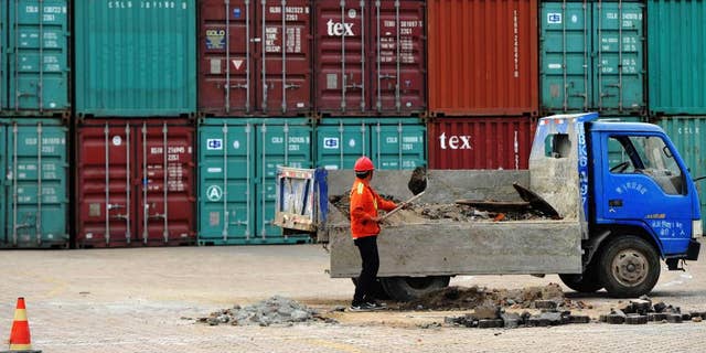A worker repairs the ground at a container port in Qingdao in eastern China's Shandong province Wednesday, June 8, 2016. China's exports and imports contracted again in May in a sign of weak global and domestic demand. (Chinatopix Via WHD) 