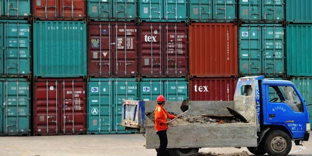 A worker repairs the ground at a container port in Qingdao in eastern China's Shandong province Wednesday, June 8, 2016. China's exports and imports contracted again in May in a sign of weak global and domestic demand. (Chinatopix Via AP)