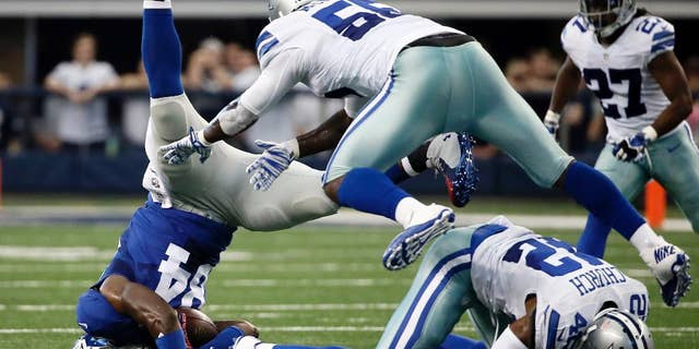 New York Giants tight end Larry Donnell (84) is upended after catching a pass by Dallas Cowboys middle linebacker Rolando McClain (55) and free safety Barry Church (42) during the first half of an NFL football game Sunday, Oct. 19, 2014, in Arlington, Texas. (AP Photo/Brandon Wade)