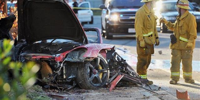 Sheriff's deputies work near the wreckage of the Porsche that crashed into a light pole and killed actor Paul Walker and Roger Rodas in Valencia, Calif., on Nov. 30, 2013.