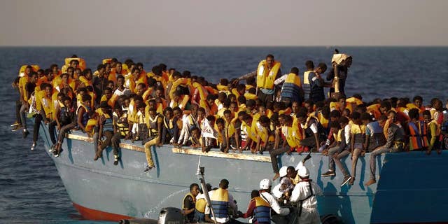 FILE - In this Monday, Aug. 29, 2016 file photo, migrants crowd onto a wooden boat as they wait to be rescued by members of an ONG at the Mediterranean sea, about 13 miles north of Sabratha, Libya. When the camera’s viewfinder is in “night vision” mode, a hidden world appears that is invisible to the naked eye in the darkness of night. Bathed in green, the view is even more dreamlike _ or nightmarish.  (AP Photo/Emilio Morenatti, File)