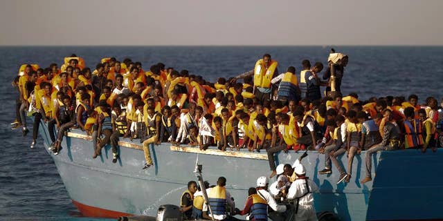 FILE - In this Monday, Aug. 29, 2016 file photo, migrants crowd onto a wooden boat as they wait to be rescued by members of an ONG at the Mediterranean sea, about 13 miles north of Sabratha, Libya. When the camera’s viewfinder is in “night vision” mode, a hidden world appears that is invisible to the naked eye in the darkness of night. Bathed in green, the view is even more dreamlike _ or nightmarish. (AP Photo/Emilio Morenatti, File)