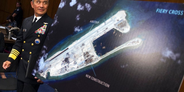 FILE - In this Sept. 17, 2015, file photo, Adm. Harry B. Harris, Jr., commander of U.S. Pacific Command, walks past a photograph showing an island that China is building on the Fiery Cross Reef in the South China Sea, as he prepares to testify on Capitol Hill in Washington before the Senate Armed Services Committee hearing on maritime security strategy in the Asia-Pacific region.