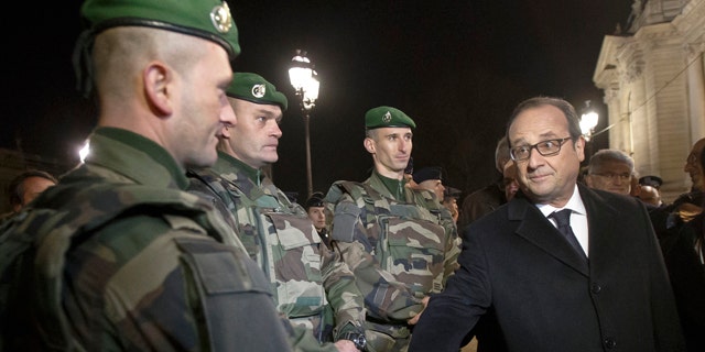 Dec. 31, 2015: France's President Francois Hollande, right, shakes hands with a foreign legionnaire as he visits the security measures at the Champs Elysees in Paris.
