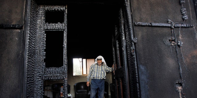 FILE - In this July 31, 2015 file photo, a Palestinian inspects a house after it was torched in a suspected attack by Jewish settlers, killing an 18-month-old Palestinian child and his parents, at Duma village near the West Bank city of Nablus.