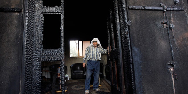 FILE - In this July 31, 2015 file photo, a Palestinian inspects a house after it was torched in a suspected attack by Jewish settlers, killing an 18-month-old Palestinian child and his parents, at Duma village near the West Bank city of Nablus.