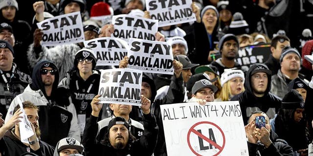 Dec 24, 2015; Oakland, CA, USA; Oakland Raiders fans hold signs that read "Stay in Oakland" in opposition of the Raiders potential move to Los Angeles during an NFL football game against the San Diego Chargers at O.co Coliseum. Mandatory Credit: Kirby Lee-USA TODAY Sports
