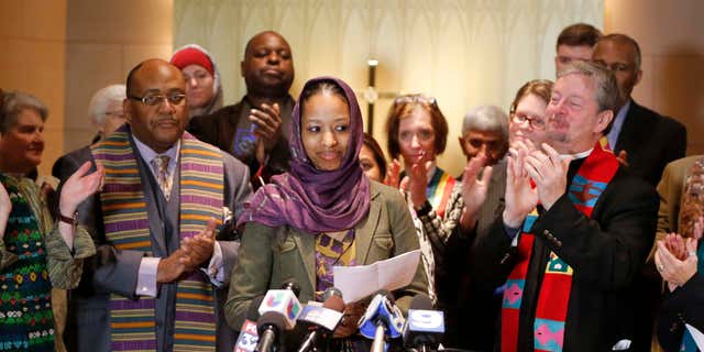 Dec. 16, 2015: Wheaton College associate professor Larycia Hawkins, center, is greeted with applause from supporters as she begins her remarks during a news conference in Chicago