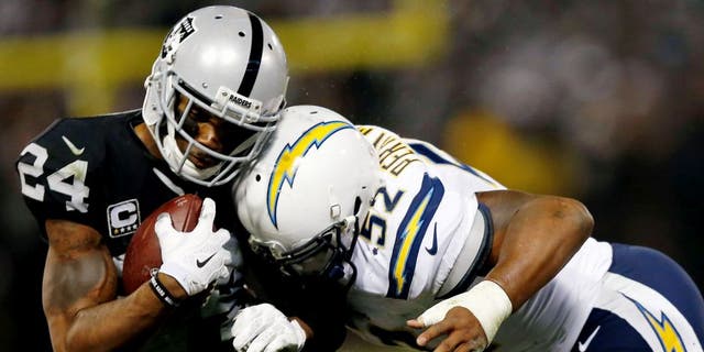OAKLAND, CA - DECEMBER 24: Safety Charles Woodson #24 of the Oakland Raiders is tackled by linebacker Denzel Perryman #52 of the San Diego Chargers in overtime at O.co Coliseum on December 24, 2015 in Oakland, California. (Photo by Lachlan Cunningham/Getty Images)