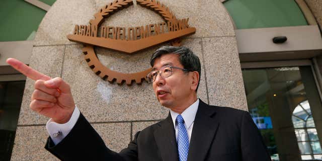 Jan. 8, 2016: Asian Development Bank President Takehiko Nakao gestures to an aide in front of the logo at the financial institution's headquarters following a forum with foreign correspondents based in the Philippines at suburban Mandaluyong city east of Manila, Philippines.