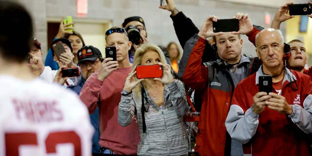 Jan. 9, 2016: Fans take pictures as the team from Alabama leaves after media day for the NCAA College Football Playoff National Championship in Phoenix.