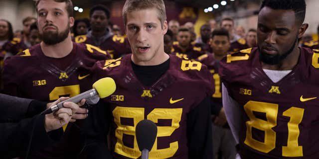 FILE - In this Dec. 15, 2016, file photo, University of Minnesota wide receiver Drew Wolitarsky, flanked by quarterback Mitch Leidner, left, and tight end Duke Anyanwu stands in front of other team members as he reads a statement on behalf of the players in the Nagurski Football Complex in Minneapolis, Minn.