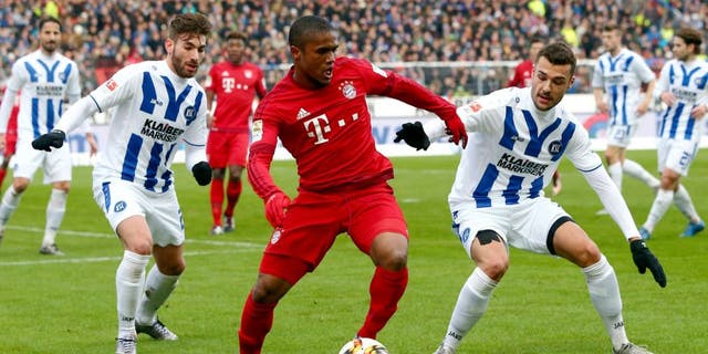 KARLSRUHE, GERMANY - JANUARY 16: Douglas Costa (C) of Muenchen is challenged by Enrico Valentini (L) and Manuel Gulde of Karlsruhe during a friendly match between Karlsruher SC and FC Bayern Muenchen at Wildpark Stadium on January 16, 2016 in Karlsruhe, Germany. (Photo by Alex Grimm/Bongarts/Getty Images)