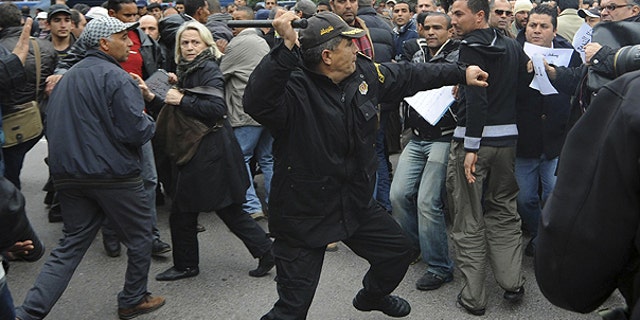 Jan. 18: A police officer faces protestors during a demonstration against the Constitutional Democratic Rally, RCD, party of Ben Ali in the center of Tunis.