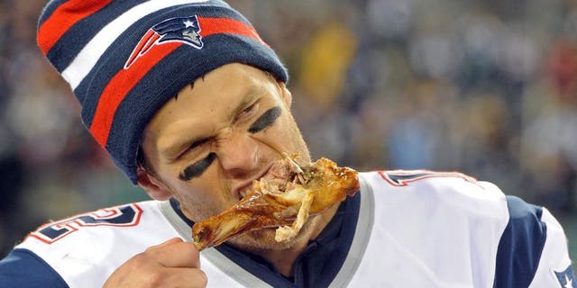 Nov 22, 2012; East Rutherford, NJ, USA; New England Patriots quarterback Tom Brady (12) takes a bite of turkey drumstick after the game against the New York Jets on Thanksgiving at Metlife Stadium. The Patriots won the game 49-19. Mandatory Credit: Joe Camporeale-USA TODAY Sports