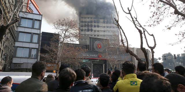 Jan. 19, 2017: Iranians watch the Plasco building where smoke rises from its windows in central Tehran, Iran.