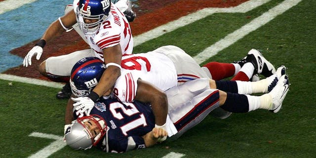 GLENDALE, AZ - FEBRUARY 03: Quarterback Tom Brady #12 of the New England Patriots is hit as he throws by defensive tackle Barry Cofield #96 and Osi Umenyiora #72 of the New York Giants in the first half during Super Bowl XLII on February 3, 2008 at the University of Phoenix Stadium in Glendale, Arizona. (Photo by Jim McIsaac/Getty Images)