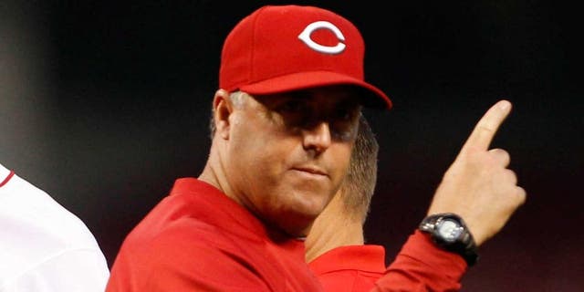 Sep 10, 2013; Cincinnati, OH, USA; Cincinnati Reds pitching coach Bryan Price (right) signals for a relief pitcher during the second after starting pitcher Tony Cingrani (52) leaves the game injured against the Chicago Cubs at Great American Ball Park. Mandatory Credit: Frank Victores-USA TODAY Sports