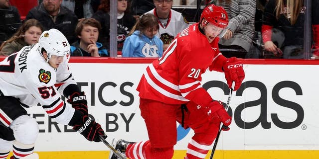 RALEIGH, NC - JANUARY 26: Riley Nash #20 of the Carolina Hurricanes gets out on a breakaway as Trevor van Riemsdyk #57 of the Chicago Blackhawks steals the puck during an NHL game at PNC Arena on January 26, 2016 in Raleigh, North Carolina. (Photo by Gregg Forwerck/NHLI via Getty Images)