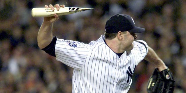 NEW YORK, UNITED STATES: New York Yankees pitcher Roger Clemens throws the broken bat of Mike Piazza of the New York Mets as Piazza runs to first base during the first inning of the Second Game of the World Series in New York City 22 October, 2000. The incident lead to a dugout emptying confrontation between the two teams. Piazza'a bat broke after hitting the ball and a piece of it flew in the direction of the mound. AFP PHOTO AFP PHOTO/Matt CAMPBELL (Photo credit should read MATT CAMPBELL/AFP/Getty Images)