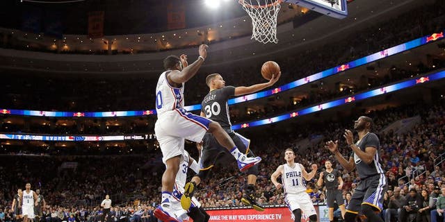 Golden State Warriors' Stephen Curry (30) goes up for a shot past Philadelphia 76ers' Isaiah Canaan (0) during the first half of an NBA basketball game Saturday, Jan. 30, 2016, in Philadelphia. (AP Photo/Matt Slocum)