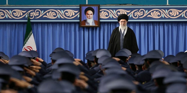 Supreme Leader Ayatollah Ali Khamenei stands as army air force and air defense salute at the start of their meeting in Tehran, Iran, Feb. 8, 2018. A portrait of the late revolutionary founder Ayatollah Khomeini hangs in the background.