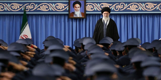 Supreme Leader Ayatollah Ali Khamenei stands as army air force and air defense salute at the start of their meeting in Tehran, Iran, Feb. 8, 2018. A portrait of the late revolutionary founder Ayatollah Khomeini hangs in the background.
