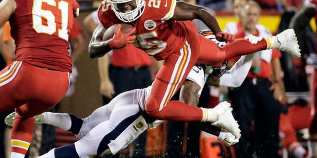 FILE - In this Sept. 17, 2015, file photo, Kansas City Chiefs running back Jamaal Charles (25) is tackled by Denver Broncos cornerback Chris Harris Jr., rear, during the second half of an NFL football game in Kansas City, Mo. Adrian Peterson and Jamaal Charles, both stalwarts for their previous clubs and with All-Pro credentials, are out there. But how many 30-plus running backs get long-term deals, even proven ones such as these? And both will want big bucks. (AP Photo/Charlie Riedel, File)