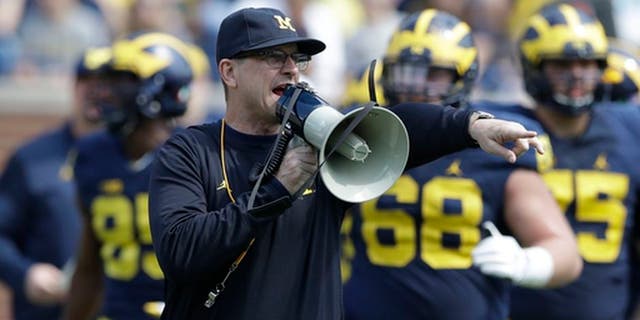 FILE - In this April 15, 2017, file photo, Michigan head coach Jim Harbaugh talks to his players during the NCAA college football team's spring game, in Ann Arbor, Mich. The increasing visibility of spring football games has offered plenty of feel-good moments and fan-friendly opportunities. What they don't provide is much insight into what these teams will be doing this fall. With so many spring games on television, teams don't want to give anything away to rival coaches who may be tuning in. (AP Photo/Carlos Osorio, File)
