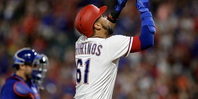 Texas Rangers' Robinson Chirinos (61) points skyward, celebrating his two-run home run, as New York Mets catcher Travis d'Arnaud walks back to the plate during the eighth inning of a baseball game, Wednesday, June 7, 2017, in Arlington, Texas. (AP Photo/Tony Gutierrez)