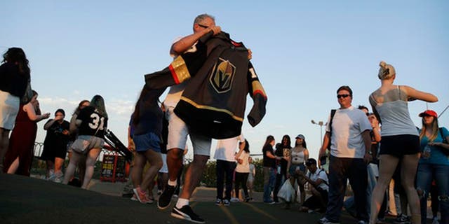 People take turns posing for photos with the NHL hockey expansion team Vegas Golden Knights' new jersey Tuesday, June 20, 2017, in Las Vegas. (AP Photo/John Locher)
