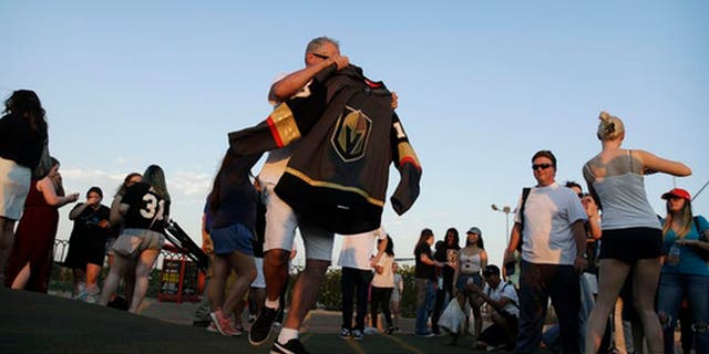 People take turns posing for photos with the NHL hockey expansion team Vegas Golden Knights' new jersey Tuesday, June 20, 2017, in Las Vegas. (AP Photo/John Locher)
