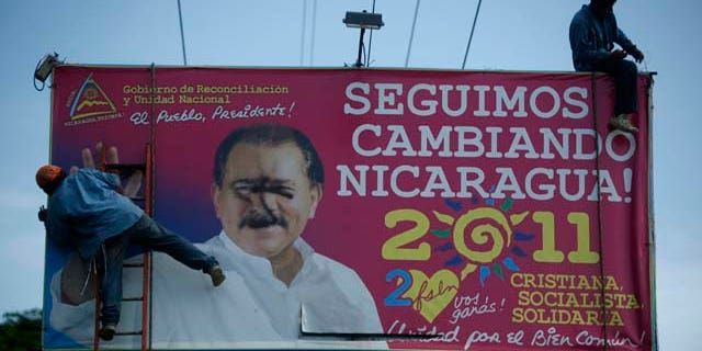 Workers remove a billboard with political propaganda supporting Nicaragua's current President Daniel Ortega that reads in Spanish "We keep changing Nicaragua: Christian, socialist, with solidarity" in Managua, Nicaragua, Thursday, Aug. 18, 2011. (AP Photo/Esteban Felix)