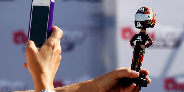 BROOKLYN, MI - AUGUST 16: A fan takes a picture of a bobblehead during practice for the NASCAR Sprint Cup Series Pure Michigan 400 at Michigan International Speedway on August 16, 2014 in Brooklyn, Michigan. (Photo by Brian Lawdermilk/NASCAR via Getty Images)