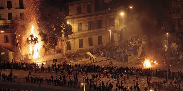 Feb. 3: Pro-Mubarak demonstrators, bottom, clash with anti-government demonstrators, top right, as a palm tree burns from a firebomb, in Tahrir Square, Cairo.