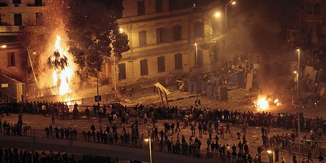 Feb. 3: Pro-Mubarak demonstrators, bottom, clash with anti-government demonstrators, top right, as a palm tree burns from a firebomb, in Tahrir Square, Cairo.