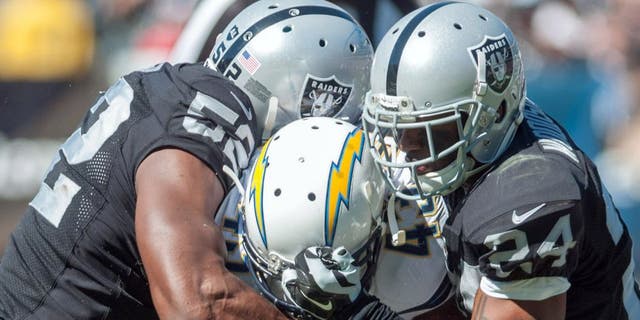 Oct 12, 2014; Oakland, CA, USA; San Diego Chargers running back Branden Oliver (43) rushes for a gain against Oakland Raiders outside linebacker Khalil Mack (52) and free safety Charles Woodson (24) during the second quarter at O.co Coliseum. Mandatory Credit: Ed Szczepanski-USA TODAY Sports