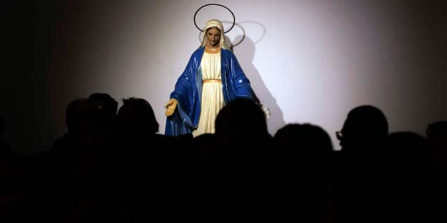 A statue of the Virgin Mary is seen in background as faithful attend a Mass celebrated by Pope Francis at the St. Mary of Setteville di Guidonia parish church, in the outskirts of Rome, Sunday, Jan. 15, 2017.