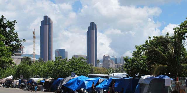 FILE - In this June 30, 2015, file photo, people camp out on a sidewalk in the Kakaako neighborhood of Honolulu, Hawaii.