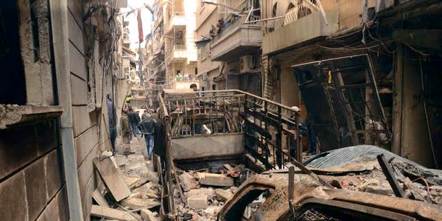 April 11, 2015: In this photo released by the Syrian official news agency SANA, Syrians gather in a street that was hit by shelling, in the predominantly Christian and Armenian neighborhood of Suleimaniyeh, Aleppo, Syria.
