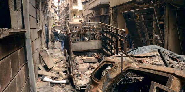 April 11, 2015: In this photo released by the Syrian official news agency SANA, Syrians gather in a street that was hit by shelling, in the predominantly Christian and Armenian neighborhood of Suleimaniyeh, Aleppo, Syria.