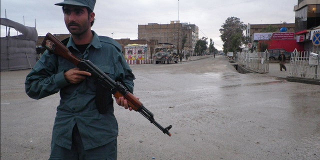 FILE: An Afghan policeman stands guard on the road leading to the Kandahar police headquarters in Kandahar south of Kabul, Afghanistan.