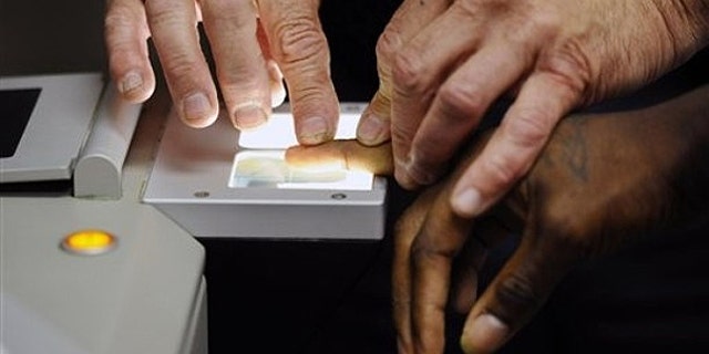 July 26, 2010: Senior Deputy Jerry Anttila fingerprints an unidentified suspect during the booking process at the Arapahoe County Justice Center in Centennial, Colo.
